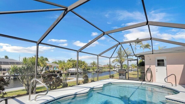A covered outdoor swimming pool with a view of a marina and palm trees.