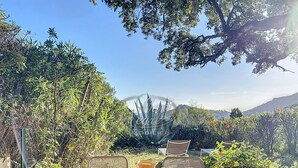 An outdoor dining area with a table set for four, surrounded by lush greenery and a view of distant hills.