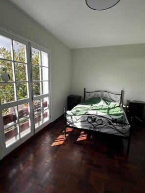 Un dormitorio con cama, mesita de noche y ventana con vistas a zonas verdes.