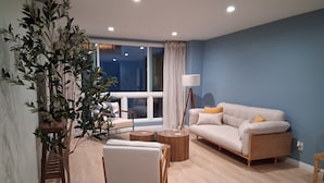 A modern living room with a sofa, a coffee table, a side table, and a floor lamp.