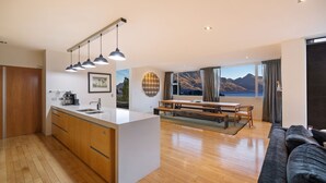A modern kitchen with a central island, wooden cabinets, and pendant lighting. - Central Sunset Charm is a stylish stay with stunning lake, mountain and city views in city centre. (Queenstown)