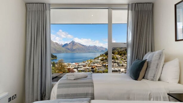 A bedroom with a large window offering a view of a lake and mountains. - Central Sunset Charm is a stylish stay with stunning lake, mountain and city views in city centre. (Queenstown)