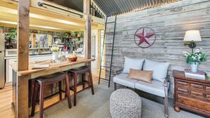 A cozy interior with a wooden bar area, a sofa, and a patterned ottoman. - Cozy Retreat w/ Ponds, Kayaks & Fire Pit (Okolona)