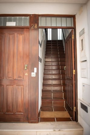 Stairs lead to a second floor, flanked by two large doors with a door number.