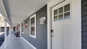 A covered porch with a white door and windows, a bicycle, and a mailbox. - 3 Mi to Main St & Beach: Coastal Cape Cod Escape! (Wareham)