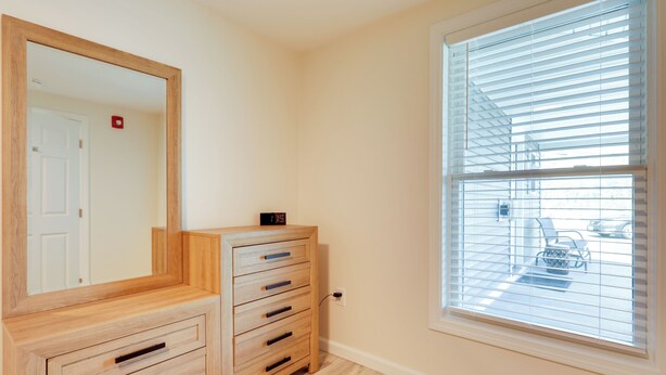 A room with a wooden dresser, a large mirror, and a window with blinds. - 3 Mi to Main St & Beach: Coastal Cape Cod Escape! (Wareham)