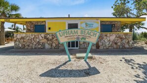 Un edificio frente a la playa con fachada de piedra, toldo amarillo y un cartel que dice "UPHAM BEACH".