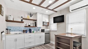 A modern kitchen with white cabinets, a wooden countertop, and a built-in microwave.