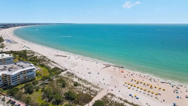A coastal hotel with a beach view, multiple floors, and a parking area.