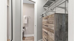 Un couloir étroit avec une commode en bois et une étagère en métal.