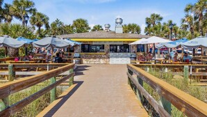 Un restaurant situé en bord de mer, doté d’une terrasse et d’un chemin en briques menant à l’entrée.