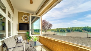 Ein Balkon mit Blick auf einen Fluss, einer Windrad-Dekoration und einer Sitzecke mit Tisch und Stühlen.