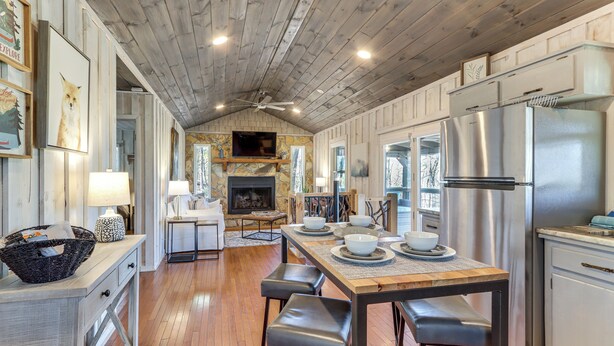 A spacious kitchen with a wooden ceiling, a central island with stools, a stainless steel refrigerator, and a fireplace. - 3 Mi to Dtwn: Blue Ridge Cabin w/ Hot Tub & Views (Blue Ridge)