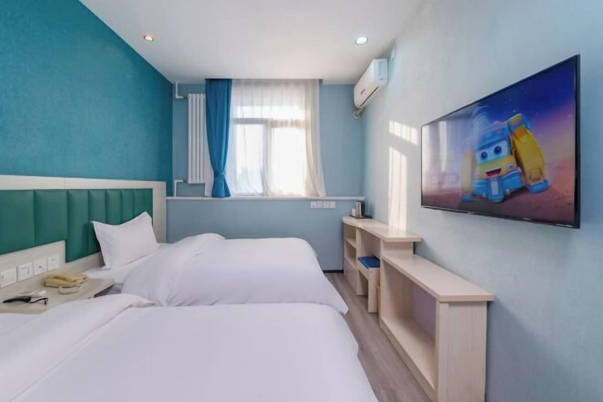 Quarto de hotel com duas camas, janela com cortinas, televisão na parede e um quadro.