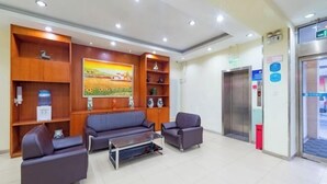 A lobby with a reception desk, a sofa, a coffee table, and a painting on the wall. - Lilai Hotel (Wendu Shuicheng store, Beijing) (Beijing)