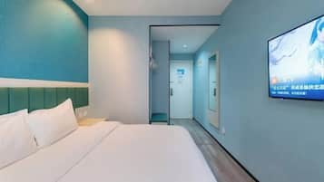 A hotel room with a bed, a TV mounted on the wall, and a door leading to another room.