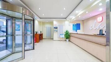 A hotel reception area with a glass entrance, a reception desk, and a wall-mounted sign.