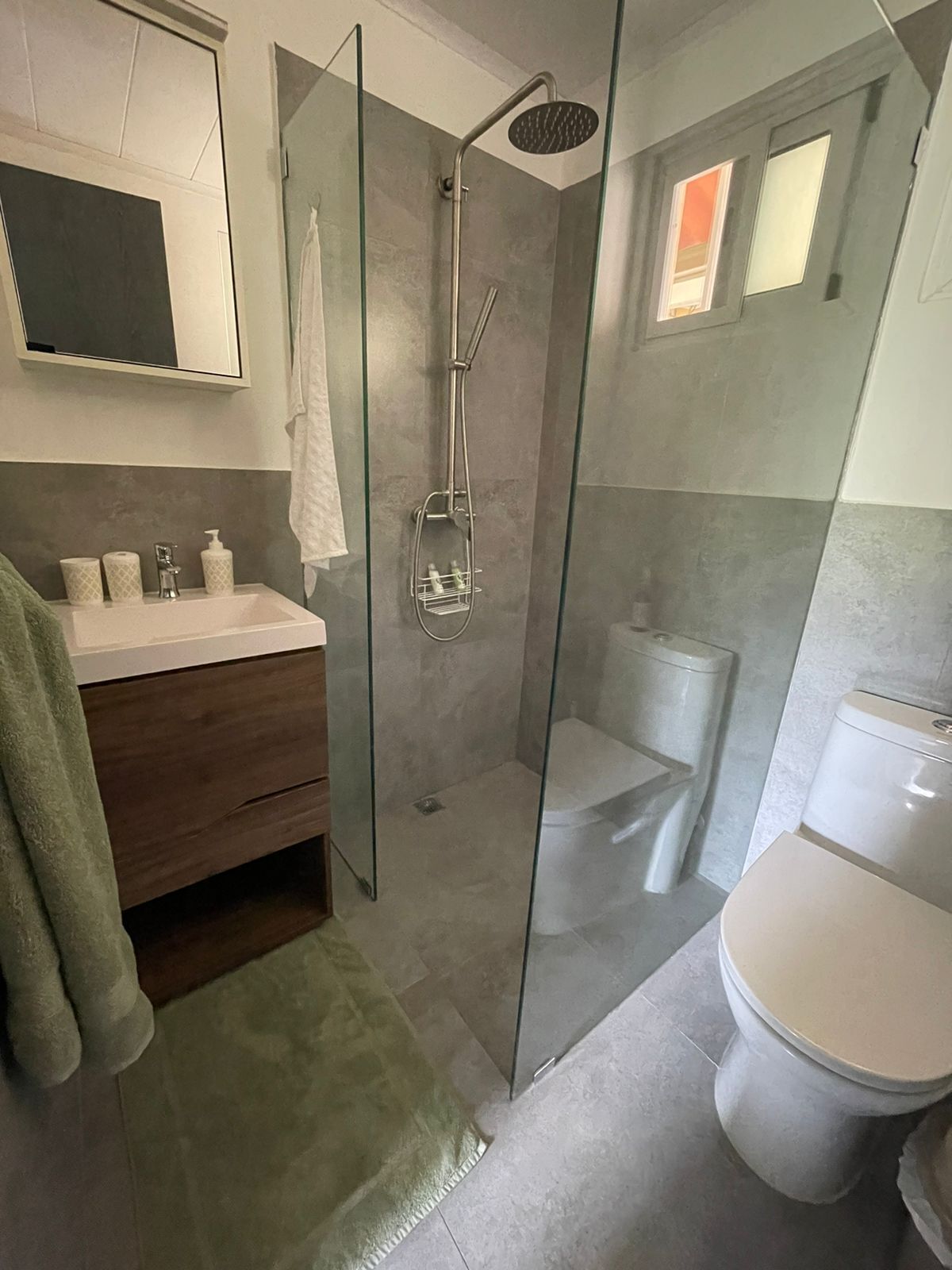 Une salle de bain moderne avec une douche à parois de verre, un meuble-lavabo avec un miroir et des toilettes.