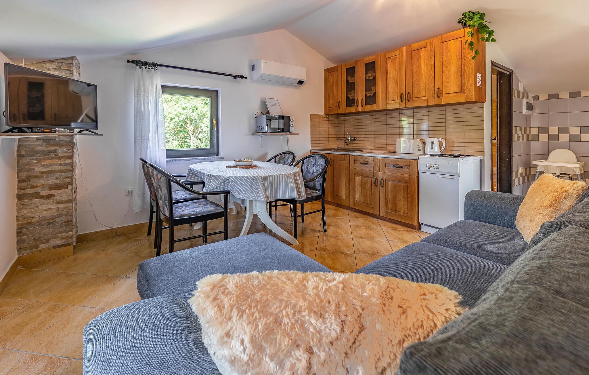 Un espace de vie compact comprenant un coin repas, une kitchenette et un canapé agrémenté de coussins moelleux.