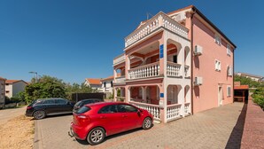 A two-story building with a balcony and a car parked in front. - Beautiful apartment in Povljana with WiFi (Povljana)