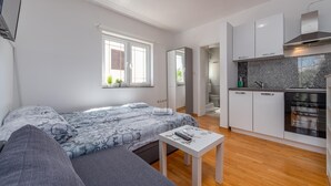 A modern apartment with a bed, a small table, a kitchen with a stove and oven, and a bathroom visible through an open door. - Beautiful apartment in Povljana with WiFi (Povljana)