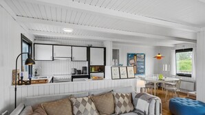 A modern kitchen with white cabinetry, a dining area with a round table, and a blue ottoman. - Pet friendly home in Saltum with WiFi (Saltum)