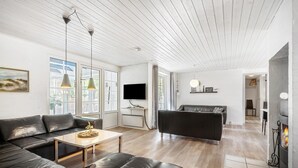 Un salon moderne avec un canapé en cuir noir, une petite table et un téléviseur fixé au mur.