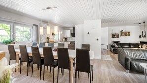 Une cuisine moderne avec des meubles blancs, un îlot central et des luminaires suspendus.