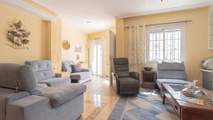 Ein Wohnzimmer mit grauen Sofas, einem Holztisch und einem gemusterten Teppich.