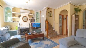 Ein Wohnzimmer mit Kamin, Fernseher und einer Treppe, die in einen anderen Raum führt.