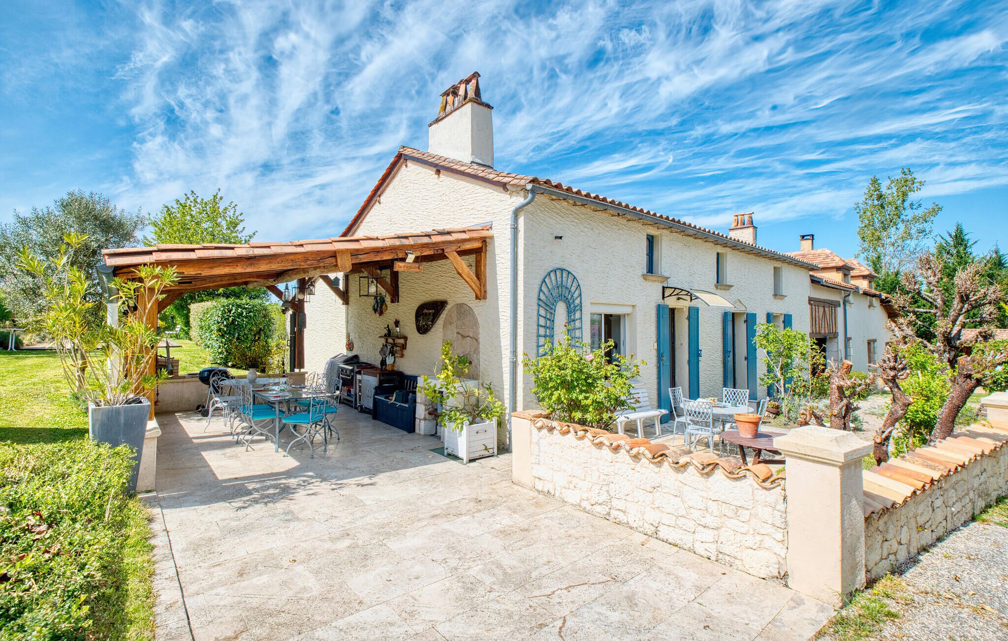 Une maison dotée d’un patio aménagé avec du mobilier d’extérieur et un barbecue.