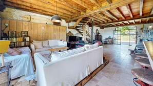 A spacious living area with a wooden ceiling, a sofa, a television, and a bookshelf.