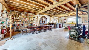 A spacious room with exposed wooden beams, a large bookshelf filled with books, a wooden bench, and a vintage motorcycle.