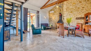 A spacious living area with a stone wall, a wooden staircase, and a dining set. - 2 bedroom awesome home in Les Lèches (Les Lèches)