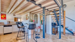 A modern kitchen with a central island, bar stools, and a staircase leading to an upper level. - 2 bedroom awesome home in Les Lèches (Les Lèches)