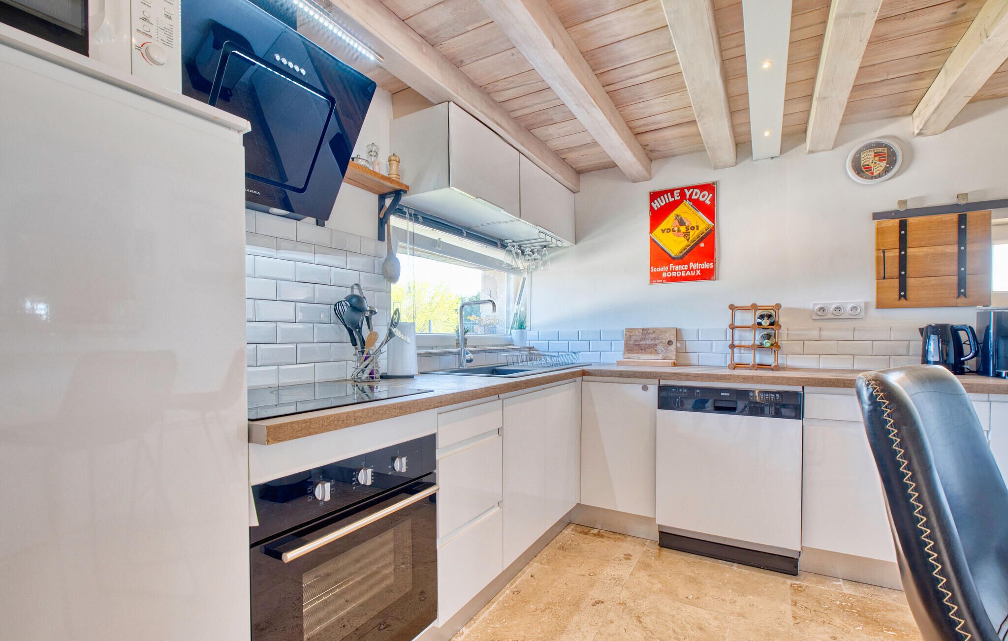 A modern kitchen with white cabinets, a black stove, and a wooden ceiling.