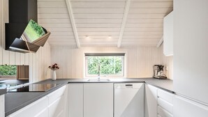 Une cuisine moderne avec des meubles blancs, un plan de travail noir et une fenêtre donnant sur un paysage verdoyant.