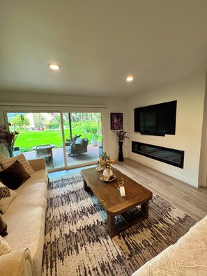 A modern living room with a sofa, coffee table, and a flat-screen TV mounted on the wall.
