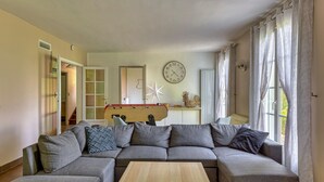 Una sala de estar con un sofá modular, una mesa de centro de madera, un reloj de pared y una decoración con forma de estrella.