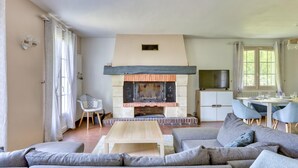 Una sala de estar con chimenea, un sofá, una mesa de centro y un comedor con televisor.