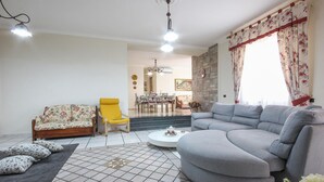A living room with a sofa, armchair, and a dining area in the background. - Villa Angela Holiday Apartment (Angri)