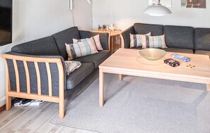 Een woonkamer met een bank, een houten stoel, een salontafel en een vloerkleed.