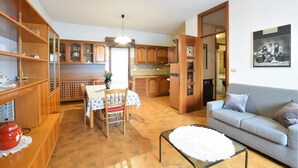 Un grand espace de vie comprenant un canapé, une table à manger avec des chaises et une cuisine à l’arrière-plan.