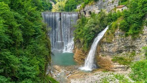 Une cascade se déversant le long d’une falaise rocheuse, entourée d’une végétation luxuriante.