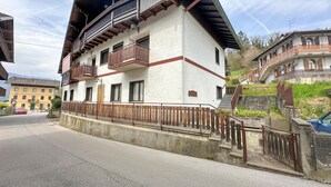 Un bâtiment à deux étages doté de balcons, d’une clôture en bois et situé devant une rue.