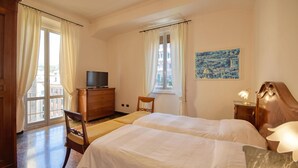 Een hotelkamer met twee bedden, een houten dressoir, een televisie en een schilderij aan de muur.