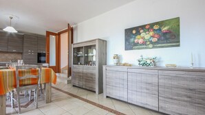 A modern kitchen with a dining area, featuring a wooden cabinet, a dining table with chairs, and a painting on the wall. - Lovely home in Avella (Avella)