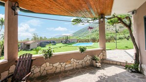 A covered patio with a pool, stone walls, and outdoor seating. - Lovely home in Avella (Avella)