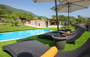 A poolside area with lounge chairs, a hot tub, and a pergola providing shade.