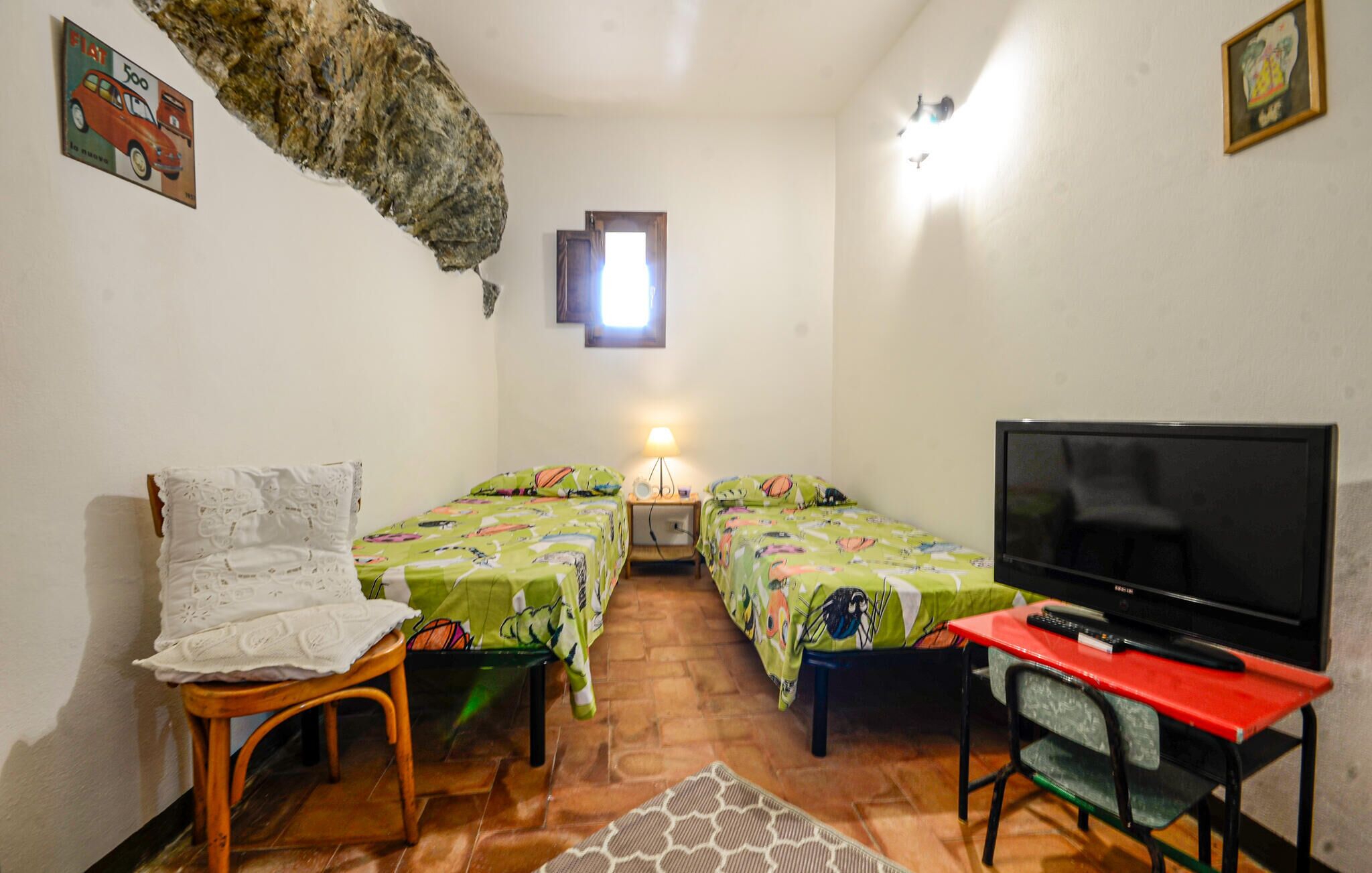 Una habitación pequeña y acogedora con dos camas, un televisor y una silla.